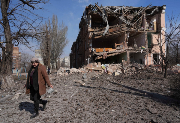 Uma mulher caminha perto de um prédio destruído por um bombardeio em Mariupol. Ucrânia, 13 de março de 2022. | Foto: Evgeniy Maloletka/AP Photo