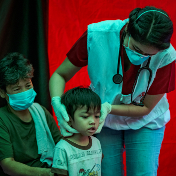 Profissional de MSF examina criança em um dos locais de busca ativa de casos de tuberculose de MSF, em Manila, nas Filipinas. © Ezra Acayan