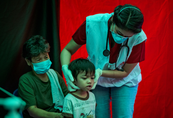 Profissional de MSF examina criança em um dos locais de busca ativa de casos de tuberculose de MSF, em Manila, nas Filipinas. © Ezra Acayan