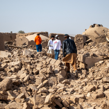 Equipe de MSF caminhando sobre os escombros de casas no vilarejo de Sanjaib, distrito de Injil, província de Herat. © Paul Odongo/MSF