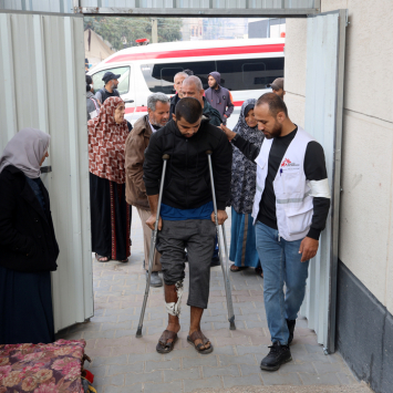 Profissional de MSF auxilia paciente com lesão na perna em uma clínica de cuidados pós-operatórios montada dentro do Hospital de Campanha Indonésio de Rafah, no sul de Gaza. Dezembro de 2023. © MSF