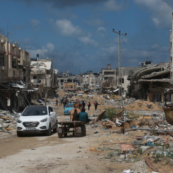 Pessoas deslocadas caminham entre prédios destruídos pela violência implacável e pelos bombardeios em Gaza. Palestina, 6 de maio de 2024. © MSF