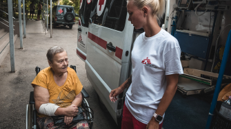 Profissional de MSF ajuda paciente a entrar em ambulância. Agosto de 2024 ©️ Olexandr Glyadyelov