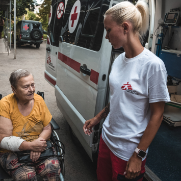 Profissional de MSF ajuda paciente a entrar em ambulância. Agosto de 2024 ©️ Olexandr Glyadyelov