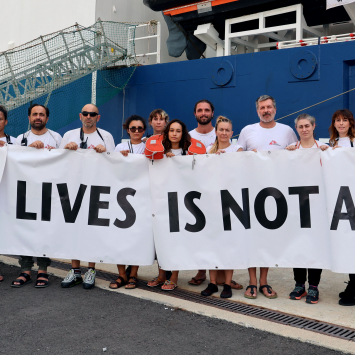 Profissionais de MSF que trabalham no Geo Barents, navio de resgate da organização, seguram faixa com mensagem “Saving lives is not a crime” (“Salvar vidas não é um crime”, em português). © Stefan Pejovic/MSF