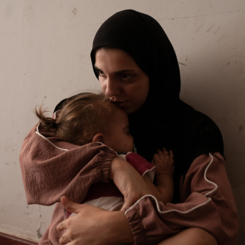 Zeinab Ozeir acalma Abbas, seu filho de 1 ano e meio, em um quarto onde vive com o marido e seus quatro filhos no abrigo Azarieh, no centro de Beirute. Líbano. © Antoni Lallican/Hans Lucas